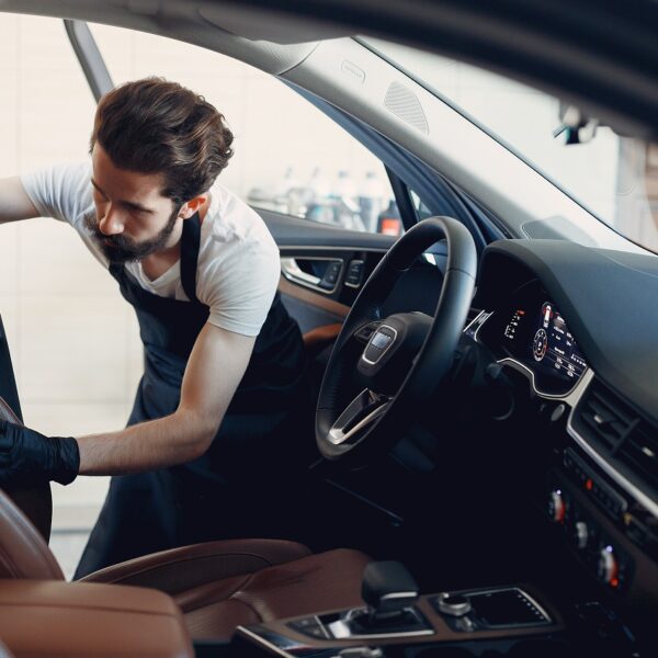 Man in a garage. Worker washing a car.